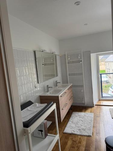 une salle de bain blanche avec un lavabo et une fenêtre dans l'établissement Les Bâtisses de 1872, à Ménéac