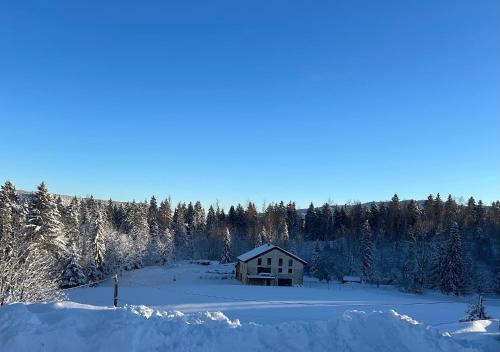 a house in the middle of a field covered in snow at Gite d'exception en pleine nature in Prémanon