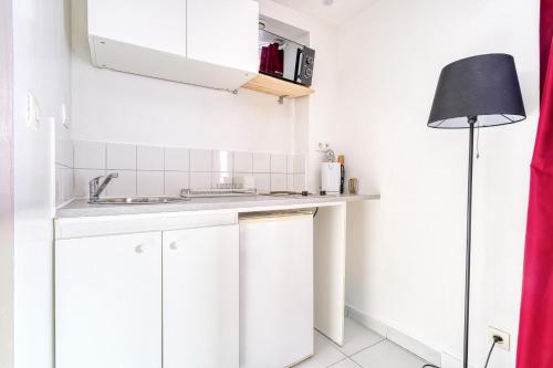 a small kitchen with a sink and a lamp at Abelia-Confort et Sérénité au coeur de la ville in Palaiseau
