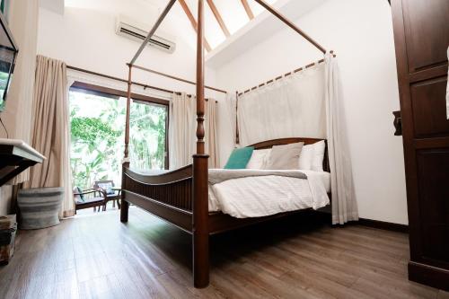 a bedroom with a canopy bed and a window at Tolani Southgate Villa Chiang Mai in Chiang Mai