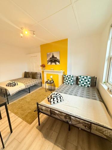 two beds in a room with yellow walls at Finsbury Park Rooms in London