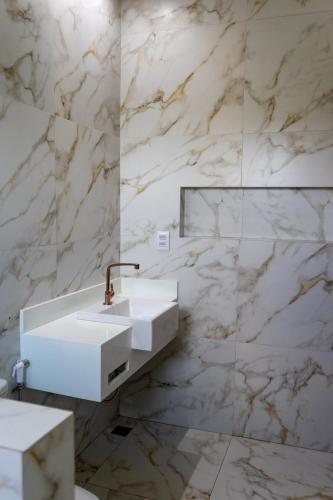 a bathroom with a white sink and marble walls at Pousada Casa Flor-Aurora -TO in Manhã