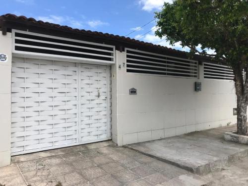 a white garage with two doors and a tree at Linhares hospedagem in João Pessoa
