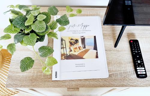 a book sitting on a table next to a plant at Stylisches 2-Zimmer Ambient Apartment in Alsternähe mit Kingsize-Bett & Schlafsofa in Hamburg