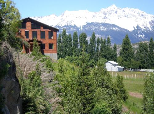 a house on a hill with a snow covered mountain at Hostal Las Natalias in Futaleufú