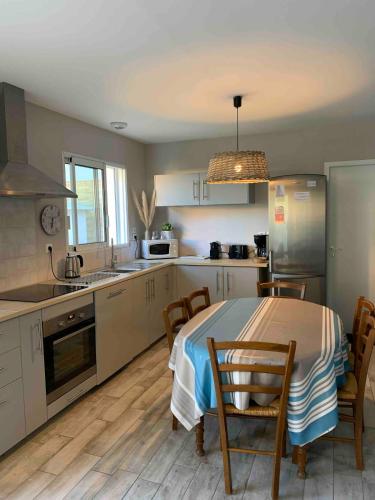 une cuisine avec une table et quelques chaises dans l'établissement Maison les pieds dans le sable 350m de la mer vélos, à Bretignolles-sur-Mer