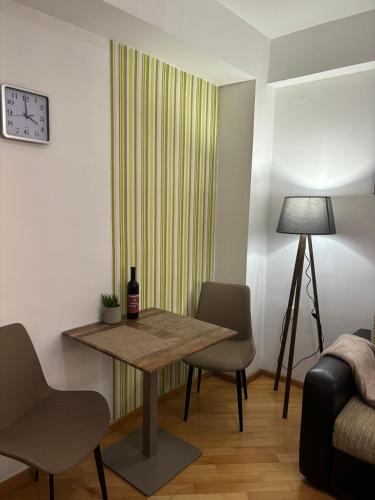 a room with a table and chairs and a clock at Lovely square apartment Purple Velvet 43 Macedonia Stree in Skopje