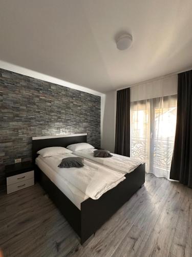 a bedroom with a large bed and a brick wall at Vila Casa Din Vale - Valiug in Văliug