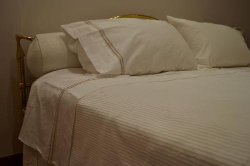 a bed with white sheets and pillows on it at Dimora Tafuri in Salerno