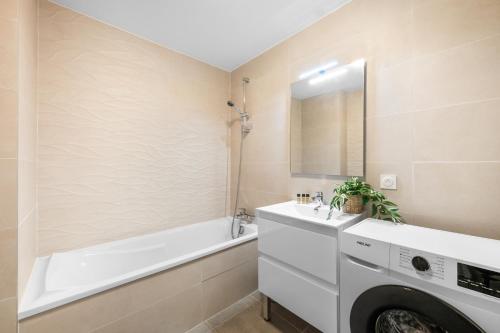 une salle de bain avec un lave-linge et une baignoire dans l'établissement Val d'Or, appartement moderne et famillial pour 4 personnes, Parking, centre gare, à Menton