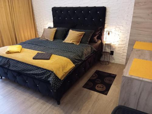 a bed with a black headboard and a yellow blanket at Black Diamond Lux - deluxe riverside apartment in Senta