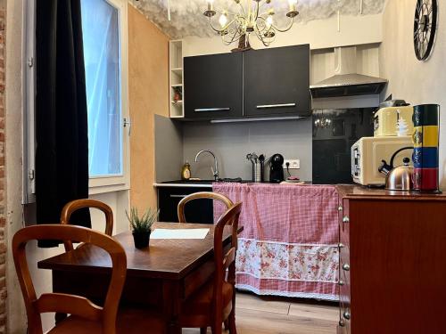 a kitchen with a wooden table and chairs and a kitchen with a counter at Le Refuge mysterieux d'Harry proche Gare Toulouse in Toulouse