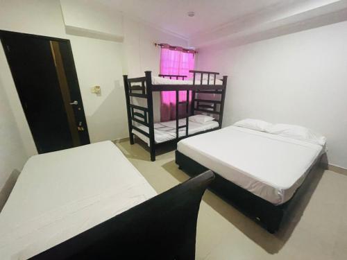 two beds in a small room with a window at Apartamentos Pinos del Rodadero in Santa Marta