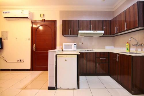 a kitchen with wooden cabinets and a white microwave at الجميرة الحديثة in Jeddah