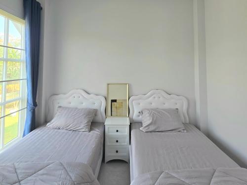 a bedroom with two beds and a dresser with a mirror at Baan Fah Chiang Rai in Mae Salong Nai