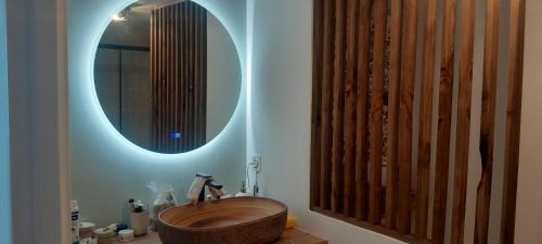 La salle de bains est pourvue d'une baignoire en bois et d'un miroir. dans l'établissement Appartement proche mer, à Mauguio