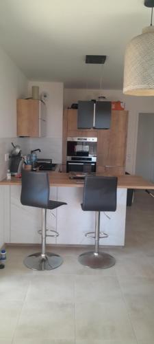 une cuisine avec deux chaises et un comptoir en bois dans l'établissement Appartement proche mer, à Mauguio
