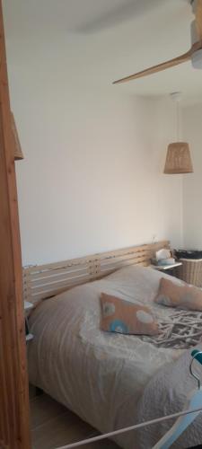 un lit avec une tête de lit en bois dans une chambre dans l'établissement Appartement proche mer, à Mauguio