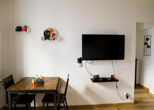 een eetkamer met een tafel en een televisie aan de muur bij Le Petit Kandinsky in Le Kremlin-Bicêtre