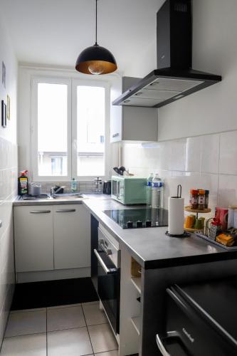 une cuisine avec des armoires blanches et un comptoir noir dans l'établissement Le Petit Kandinsky, au Kremlin-Bicêtre