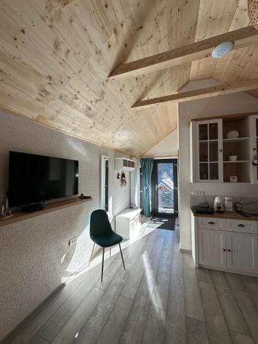 a kitchen with a chair and a television on the wall at Casa din Vale apartament - Valiug in Văliug