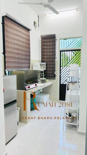 a kitchen with a refrigerator and a table at Homestay Rumah 2081 in Tumpat