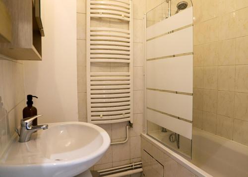 une salle de bain avec un lavabo et une douche dans l'établissement Le Petit Parisien, au Kremlin-Bicêtre