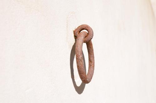 an old rusty hook hanging on a white wall at Casa Rural El Vihuelo in El Bosque