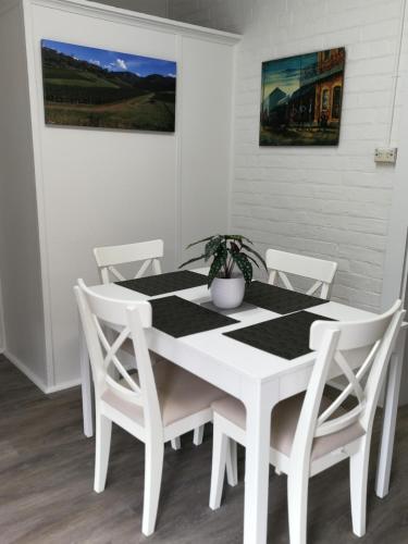 a white dining room table with white chairs and a plant at Merala a cosy cottage with easy stroll to CBD in Mudgee