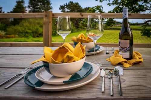 a table with a bottle of wine and plates and glasses at Lowern, Luxury Lodge with Hot Tub and Games Room in Menai Bridge