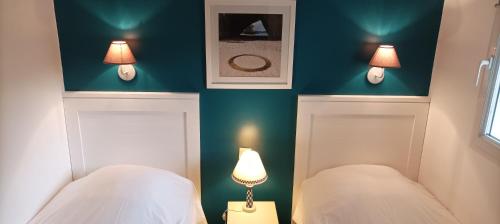 - 2 lits dans une chambre avec 2 lampes sur le mur dans l'établissement T2 Résidence avec piscine chauffée de mai à sept, à Saint-Jean-dʼOrbetiers