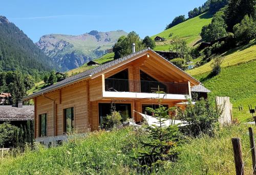 a wooden house on a hill with mountains in the background at Ferienwohnung Ausspannen und Geniessen in Engi