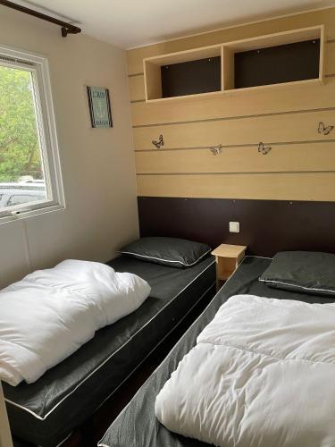 deux lits assis dans une pièce avec une fenêtre dans l'établissement Mobile-home IRM Casita 3 Bedrooms - La Palmyre Bonne Anse Plage, aux Mathes