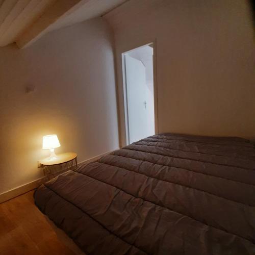 une chambre avec un lit et une lampe sur une table dans l'établissement appartement calme et lumineux , centre ville et plage à pied, à Pornichet