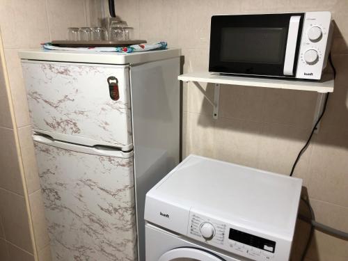 a small kitchen with a microwave and a washing machine at JM House in Viseu