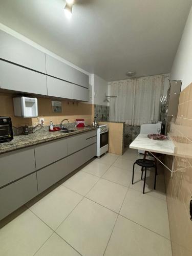a kitchen with white cabinets and a table in it at Apartamento quadra mar, 1 dos quartos com ar-condicionado , Barra Sul in Balneário Camboriú