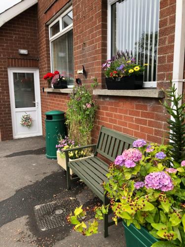 a green bench in front of a brick building with flowers at Old Egg Shop in Holywood