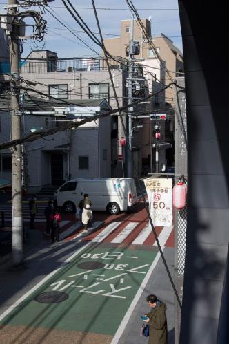 a person standing on a street with a green crosswalk at 全新装修南品川haven春 in Tokyo