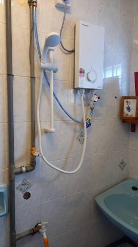 a shower in a bathroom with a hose on the wall at Bentong Hill Cottage in Bentong