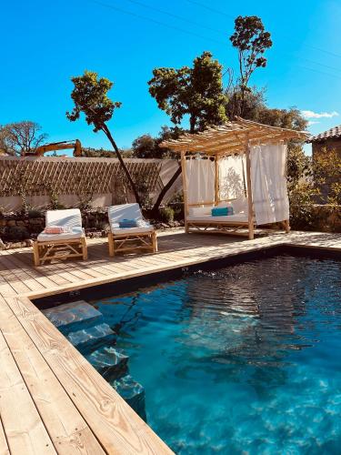 - une piscine avec un kiosque et des chaises à côté de la piscine dans l'établissement bergerie-ucaseddu, à Zonza