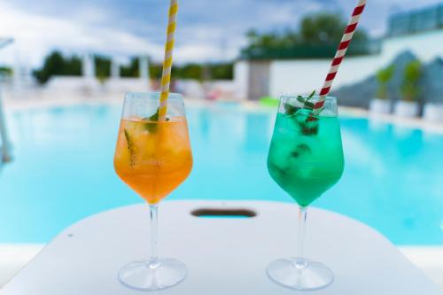 two glasses of drinks sitting on a table next to a pool at Vesuvio Inn Bed & Wine Experience in Boscotrecase