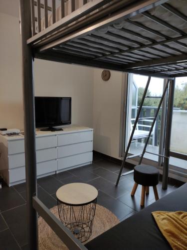 Cette chambre comprend une mezzanine avec une télévision et un tabouret. dans l'établissement appartement proche plage avec piscine, à La Baule