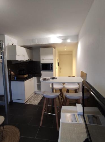 une cuisine avec un comptoir blanc et quelques tabourets dans l'établissement appartement proche plage avec piscine, à La Baule