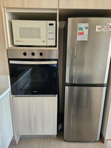 a microwave and a refrigerator in a kitchen at Claro Centro Temuco in Temuco