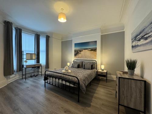 a bedroom with a bed and a desk and windows at Belford Apartment 1, Close to Tynemouth in Tynemouth
