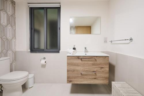 a white bathroom with a toilet and a sink at Galea Hospitality - Caravaggio in Xagħra