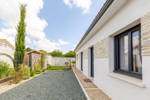une maison blanche avec une cour avec une fenêtre dans l'établissement Charmante maison proche plage, à Meschers-sur-Gironde