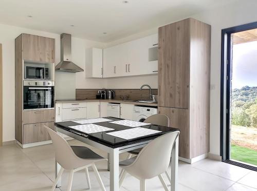 une cuisine avec une table et des chaises dans une cuisine dans l'établissement Bas de villa contemporaine avec vue dégagée, à Alata