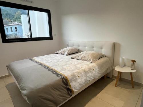 Ce lit se trouve dans une chambre dotée d'une fenêtre et d'une table. dans l'établissement Bas de villa contemporaine avec vue dégagée, à Alata