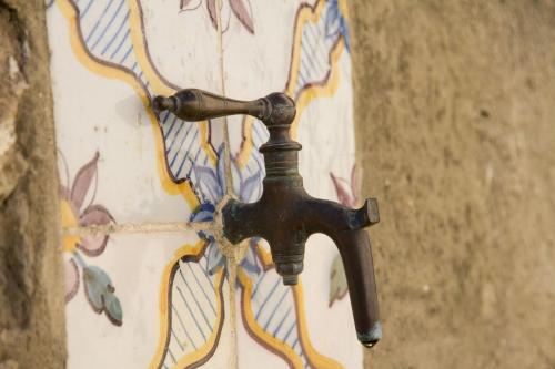 a bronze water faucet attached to a wall with graffiti at Casa Rural El Vihuelo in El Bosque